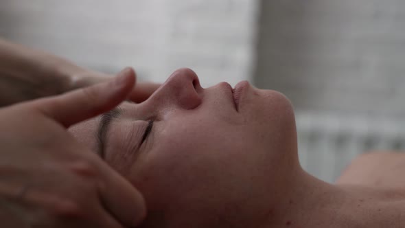 Beautician is Massaging Face of Adult Woman Relaxing Procedure for Rest and Rejuvenate Closeup