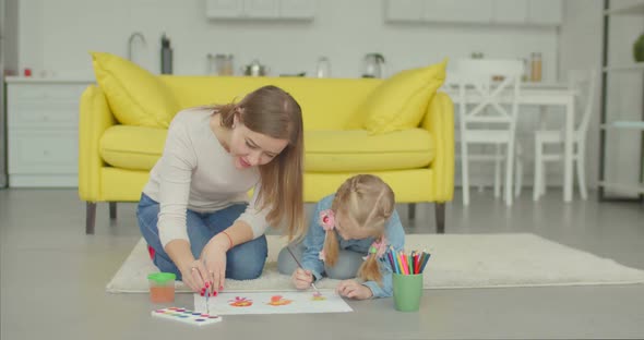 Cute Girl with Mother Making Painting at Home