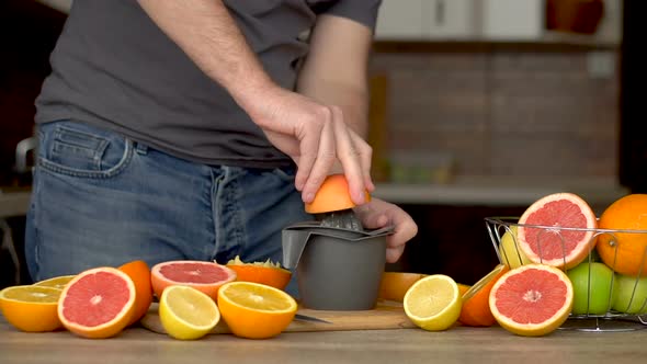 A Man Squeezes Orange Juice with Citrus Juicer