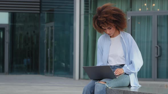 Curly African American Woman Student Girl Female Freelancer User Worker Sitting on Street Outdoors