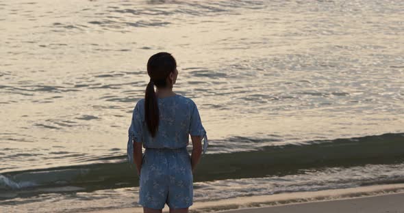 Woman stand on the beach and enjoy the view of the sea at sunset time