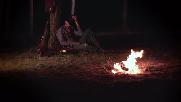 Cowboy Near the Fire in the Forest at Night