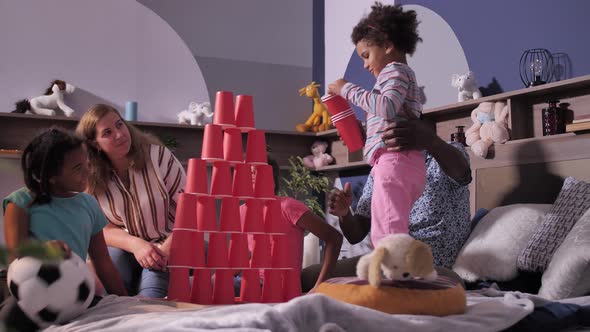 Cute Little Girl Playing with Loving Family on Bed