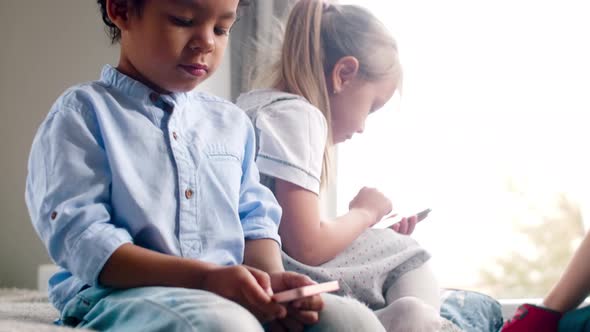 African Boy and Caucasian Girl Playing on Smartphones