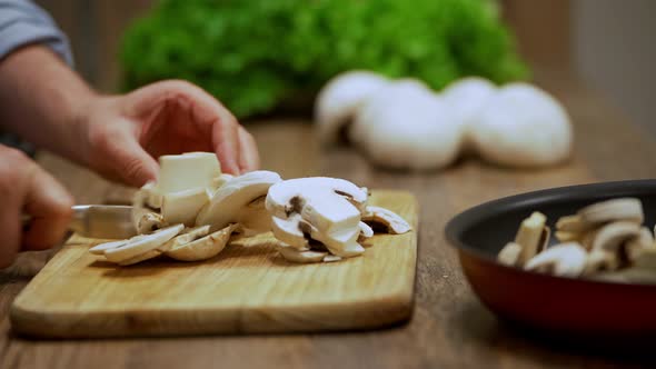 a man cuts champignon mushrooms. cooking process by the chef. salad ingredients. caring man