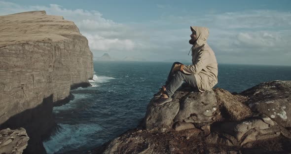 Man sits at the edge of a cliff