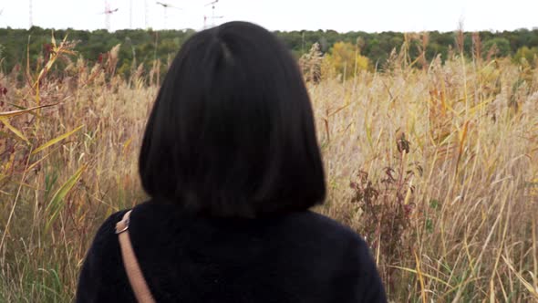 Following shot of female walking through high grass on autumn day