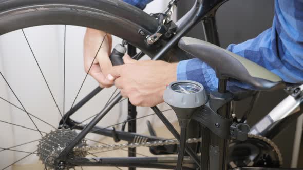 Bicycle mechanic inflating bike wheel. Cyclist pumping air into bike wheel tire.