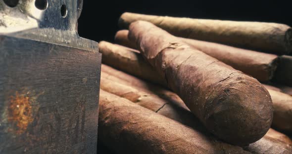 View through a cigar cutter. Cigars in humidor with lighter.