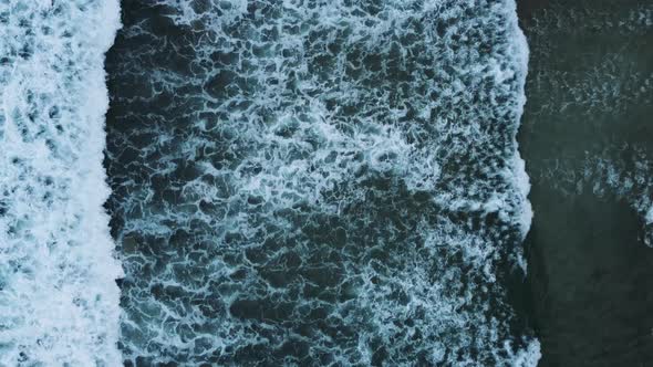 Flying over the ocean (Norway) looking down at the waves while zooming out. The beach gets into the