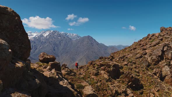 Tourist backpacker hiking in High Atlas with Toubkal massif in the distance