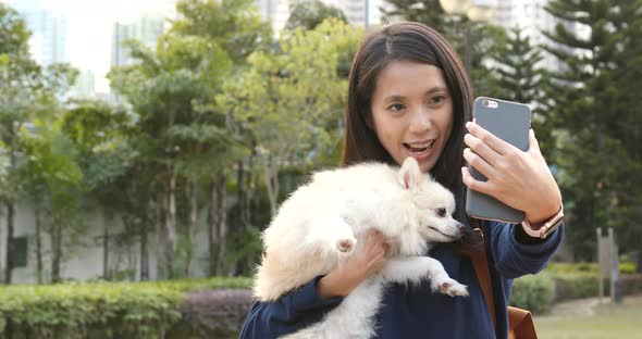 Woman taking selfie on mobile phone with her dog