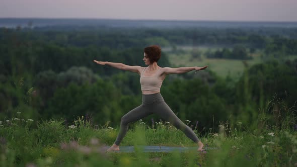 Slow Motion Young Woman in Tracksuit Practices Yoga Position in the Mountains