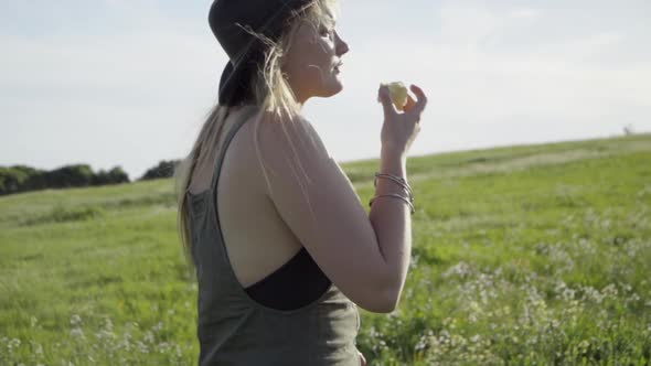 SLOMO of Young Woman Eating an Apple in a Field of Flowers