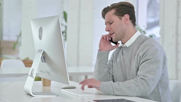 Young Man Talking on Smartphone in Office 