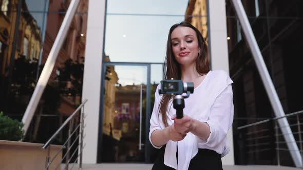 Video Blogging. Woman With Camera Near Modern Business Building