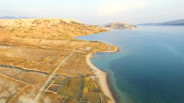 Flying above isolated house in yellow grass of Pag island, Croatia