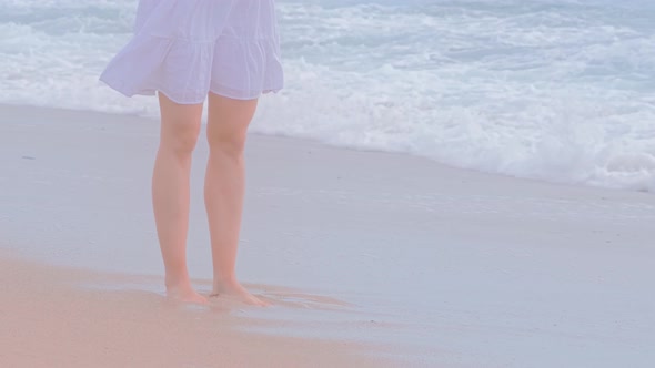 Woman in White Dress on Sand Beach.