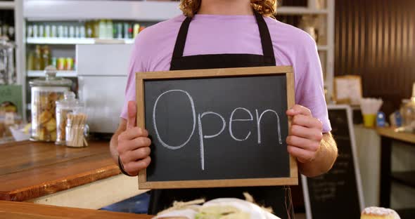 Waiter holding chalkboard with open sign