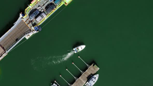 Aerial view of a boat leaving a harbor, near a cable ferry, at a dock, in the archipelago of Porvoo,