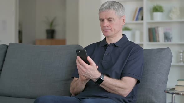 Attractive Middle Aged Businessman Using Smartphone on Sofa