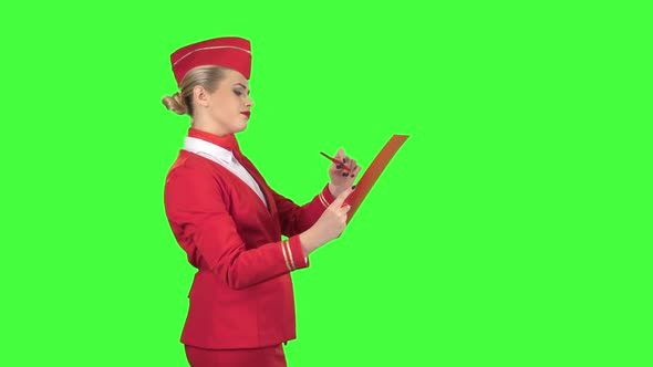 Girl Writes a Pen in a Special Folder, She Is a Flight Attendant. Green Screen. Side View