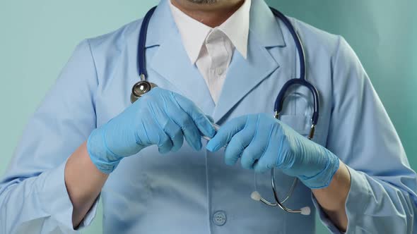 Doctor in Professional Medical Suit and Blue Gloves Checking Temperature By Digital Thermometer