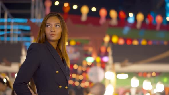 Stunning young woman smiles at the camera under the bright lights of the city