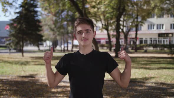 Young Happy Man Cheering Success in Sunset Light, Gesture of Thumbs Up