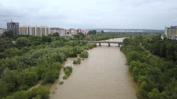 Aerial view of wide dirty river with muddy yellow water flowing through a city in flooding period alt