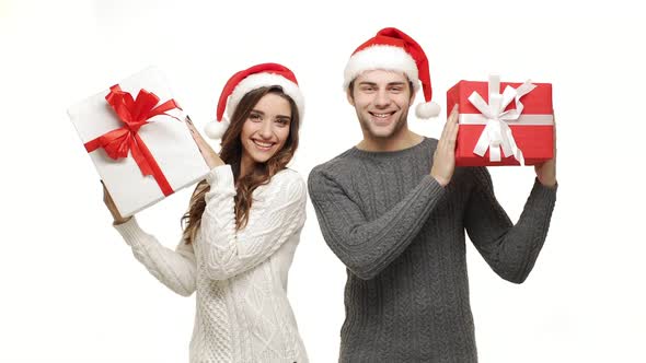  Young Couple Playing and Hiding Behind Christmas Present Box on White Isolated Background