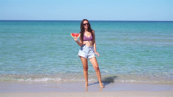 Happy Girl Having Fun on the Beach and Eating Watermelon