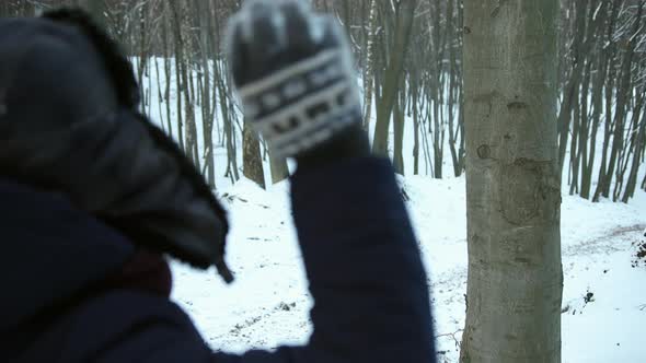 Man Throws Snowball at a Tree Trunk