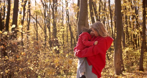 Young Blond Mother with Daughter Walk in the Autumn Forest