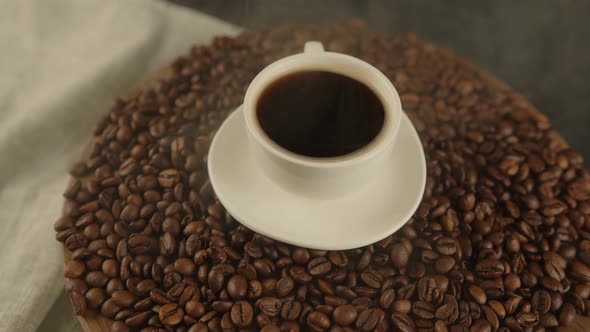 Cup of Coffee and Saucer on Coffee Beans with Dissipating Steam