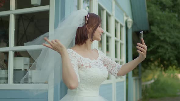 30s Bride in White Wedding Dress Taking Selfie Photos Standing Near Rural House