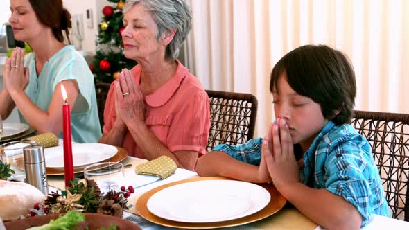 Extended family saying grace before christmas dinner