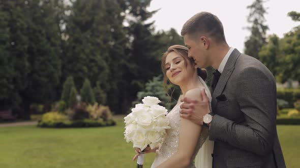 Newlyweds Caucasian Groom with Bride Walking Embracing Hugs in Park Wedding Couple