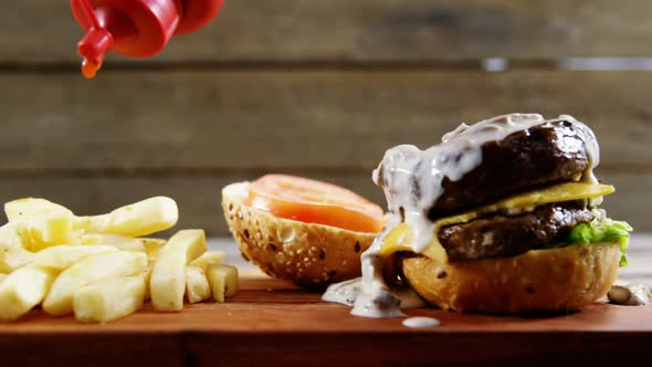 Ketchup being squeezed over hamburger on tray