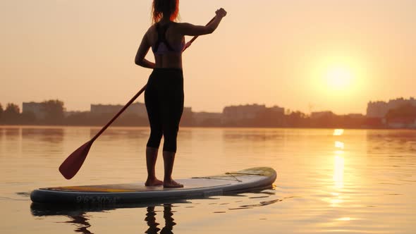 Sunset Woman Silhouette on Lake Stand Up Paddle Board SUP Slow Motion View