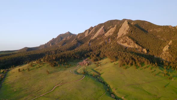 Beautiful early morning sunrise shining warm light on Colorado Flatiron mountains, trees, and Chauta