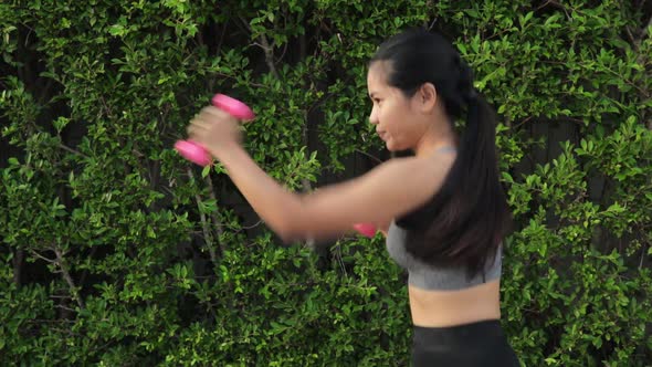Thai Woman Punching With Pink Dumbbells - Outdoor Exercise. - medium shot