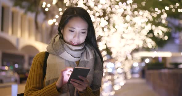 Woman look at mobile phone in city at night