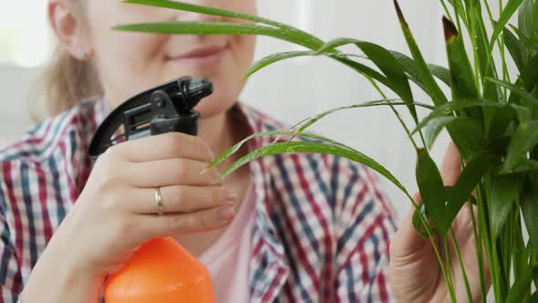 Portrait of Smiling Young Woman Gardening at Home and Watering Plants with Sprinkler