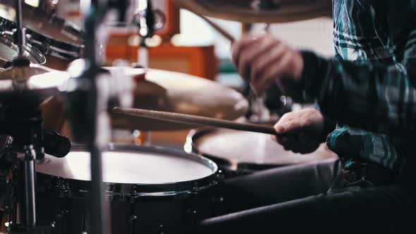 Inspired Man in Blue Plaid Shirt Playing Drums