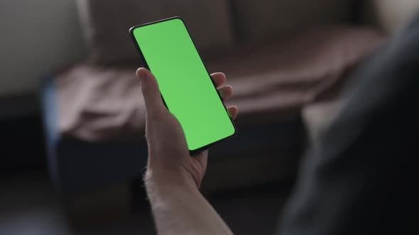 Man Use Smartphone with Green Screen While Standing in Living Room