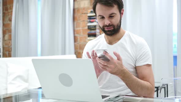 Beard Man Browsing Online on Smartphone Typing Message