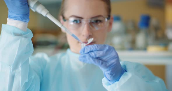 Female Scientist with a Pipette Analyzes a Liquid at Laboratory