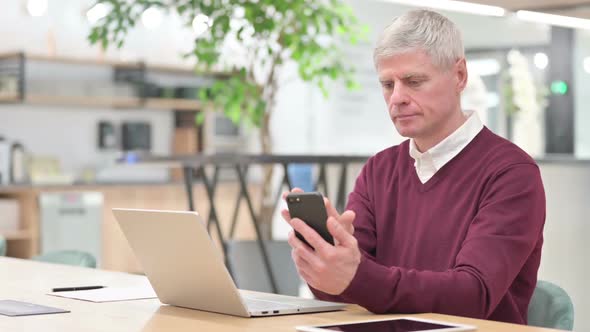 Middle Aged Man Using Smartphone at Work