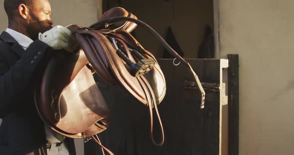 African American man preparing the saddle of the Dressage horse